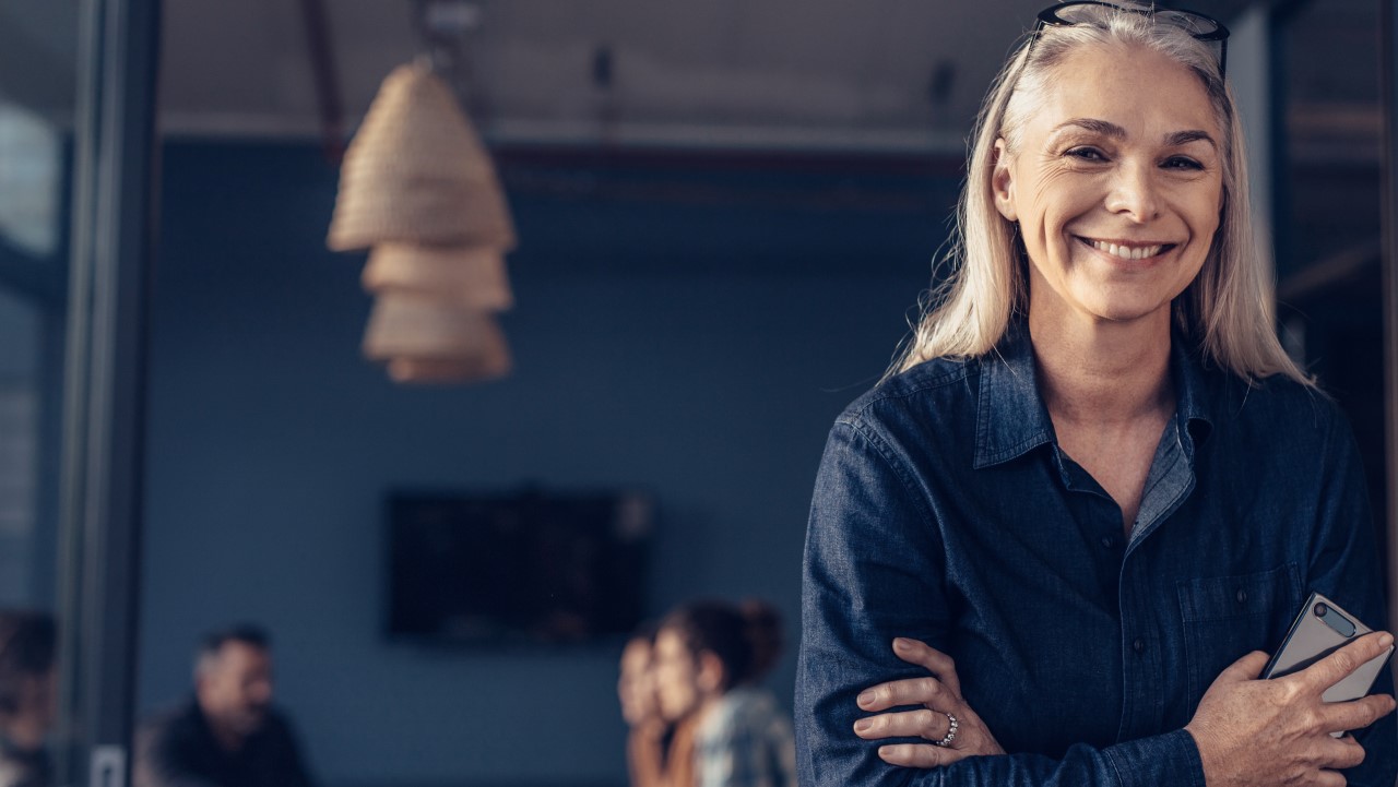 Smilende dame på kontor med mobil